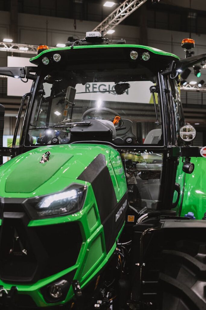 A close-up of a vibrant green tractor on display at an indoor exhibition.