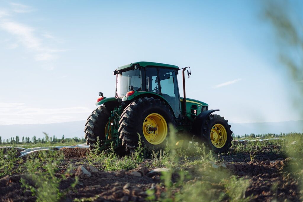 A vibrant green tractor on a farm in Mendoza, Argentina, under clear blue skies.